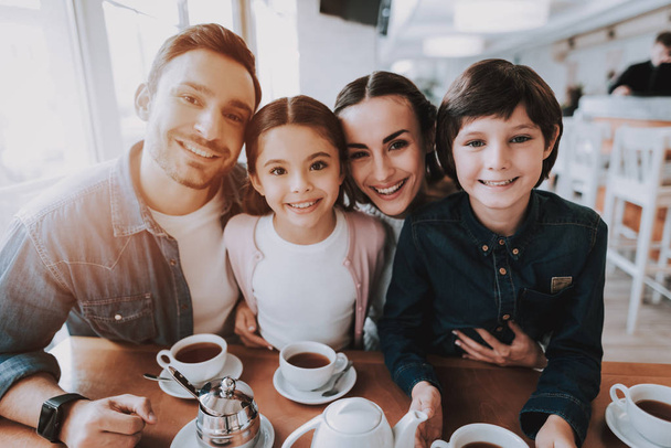 Family Resting in Cafe. Family is a Mother, Father, Daughter and Son. People is Doing Photo on Camera. People is Happy and Smiling. Persons is Sitting at Table. Family Portrait. Sunny Daytime. - Fotografie, Obrázek