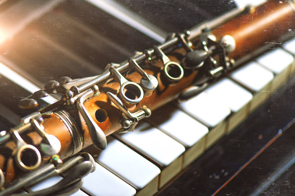 Vintage-efektivalokuva. Antiikki klarinetti nojaa piano näppäimistö
. - Valokuva, kuva