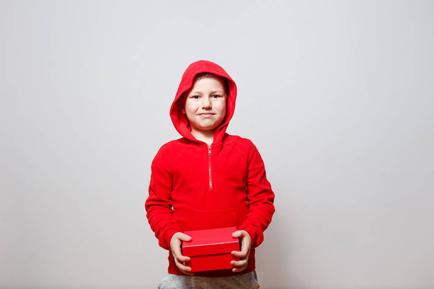 the boy in the Red a hoodie with red gift box in your hands - Фото, изображение