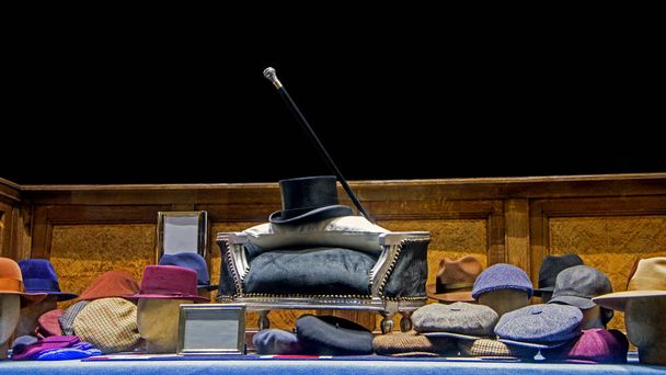 Composición de los sombreros apilados varios hombres de color para la venta con bastón y sombrero alto en un centro aislado sobre fondo negro
 - Foto, Imagen
