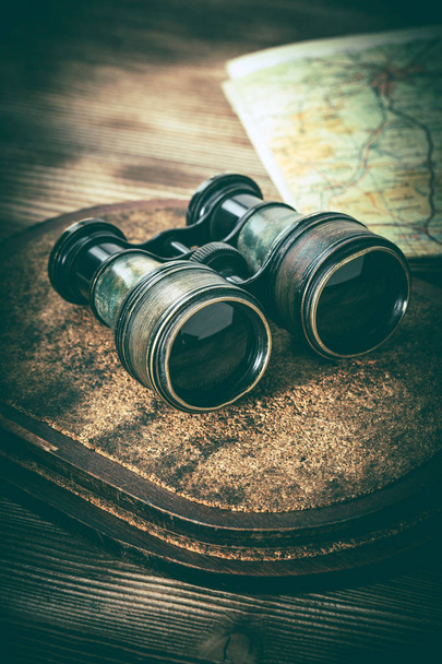 Old binoculars covered with patina on a wooden background. - Zdjęcie, obraz