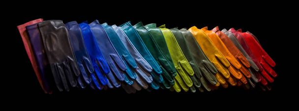 Rangée de gants en cuir coloré isolés sur fond noir
 - Photo, image