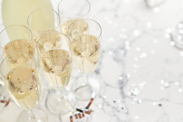 Copas de champán y botella colocadas sobre fondo de mármol blanco - Foto, Imagen