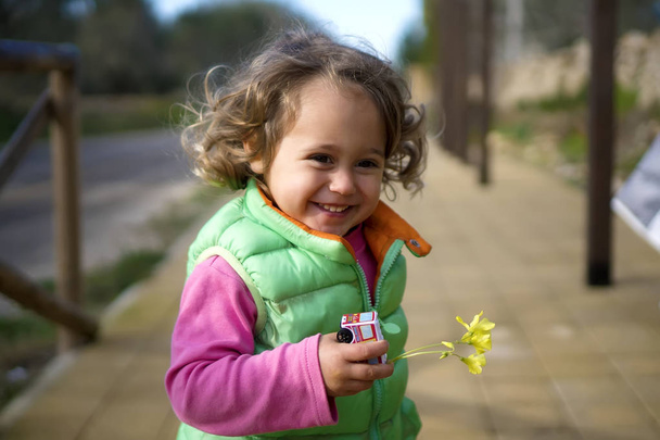niña 2-3 años de edad en chaleco verde corre sonriendo
 - Foto, imagen