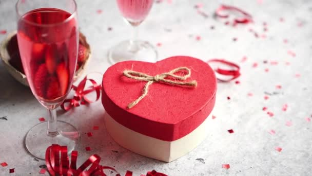 Láhev z růžové šampaňské, brýle s čerstvými jahodami a dárek ve tvaru srdce - Záběry, video