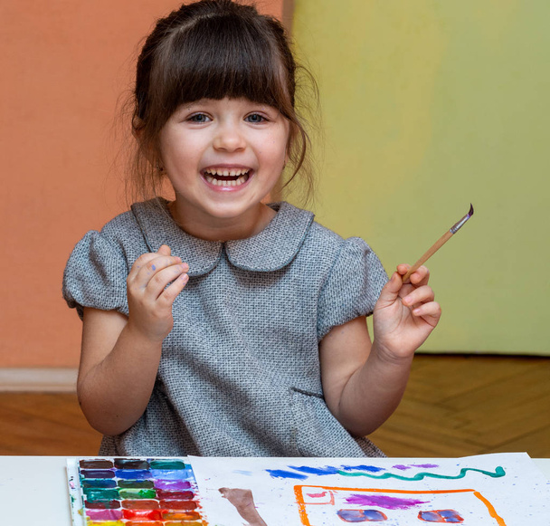 Mała dziewczynka europejskiego malarstwa w tabeli wewnątrz. Rysunek w jej Przedszkole w domu dziecka - Zdjęcie, obraz