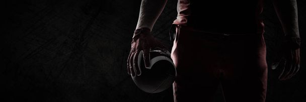 American football player standing with rugby ball against panoramic shot of grunged concrete wall - Foto, afbeelding