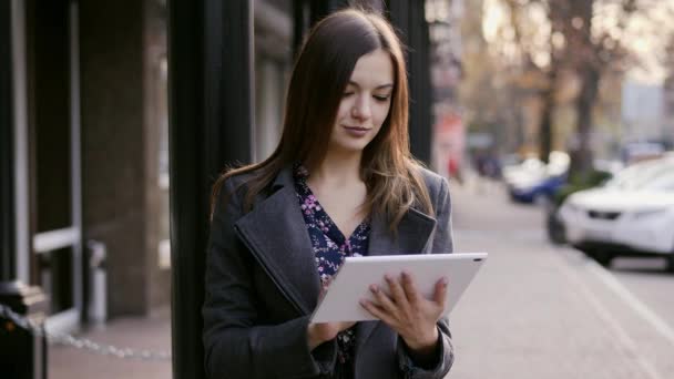 Retrato de cerca de la hermosa joven empresaria que utiliza el dispositivo de tableta en la calle en la puesta de sol cerca del hotel de negocios
 - Metraje, vídeo