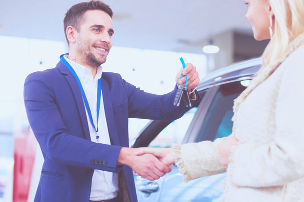 Image of car dealer handshaking with happy female in automobile center - Фото, изображение