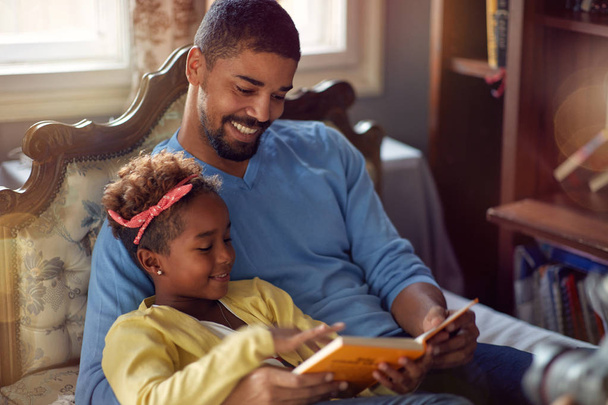 Father and daughter spending Christmas time together, daddy reading fairy tales at home - Foto, Imagen