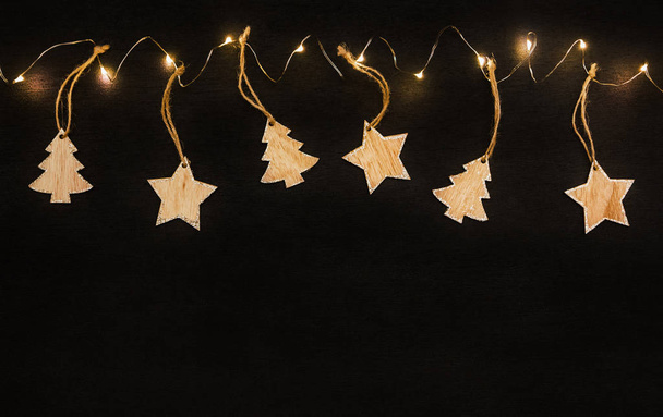 ξύλινα αστέρια και ένα χριστουγεννιάτικο δέντρο σε μαύρο φόντο - Φωτογραφία, εικόνα