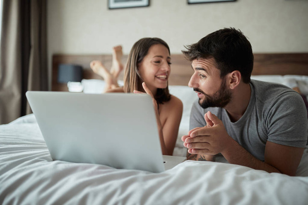 Happy young couple is having fun in bed together - Φωτογραφία, εικόνα