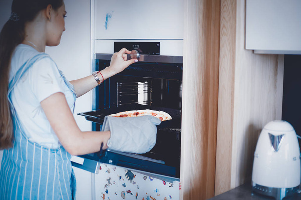 Gelukkig jong vrouw koken pizza thuis - Foto, afbeelding