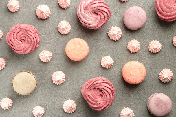 Sweets on grey concrete background: macarons, marshmallow and meringue of different pastel colours. A pattern of colorful french cookies, marshmallow and meringue. Valentine's Day background - Photo, image