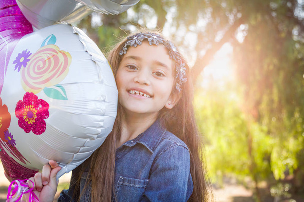 Νέοι χαριτωμένο μικτή φυλή κορίτσι εκμετάλλευση Mylar μπαλόνι σε εξωτερικούς χώρους. - Φωτογραφία, εικόνα