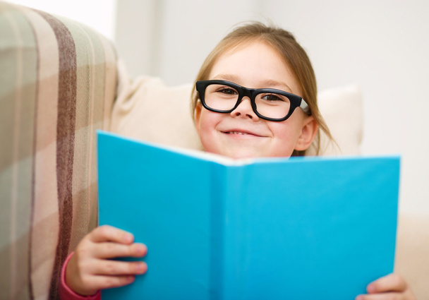 Little girl is reading a book - Фото, изображение
