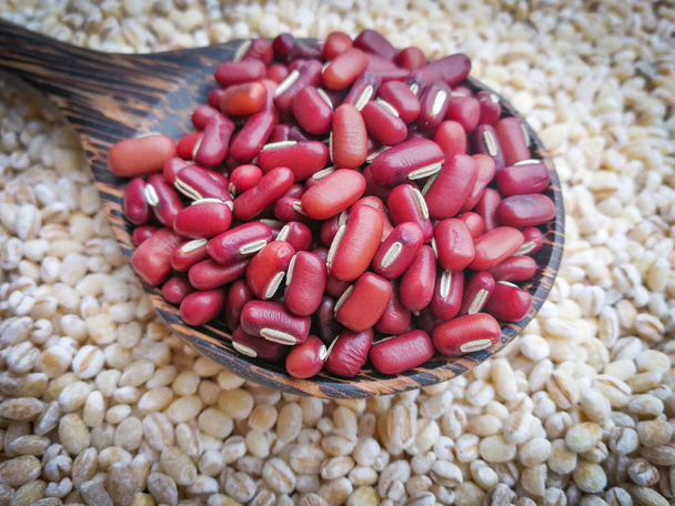 семена фасоли красного цвета на ложке / зерне или зерновых бобов со слезами Иова на заднем плане
  - Фото, изображение
