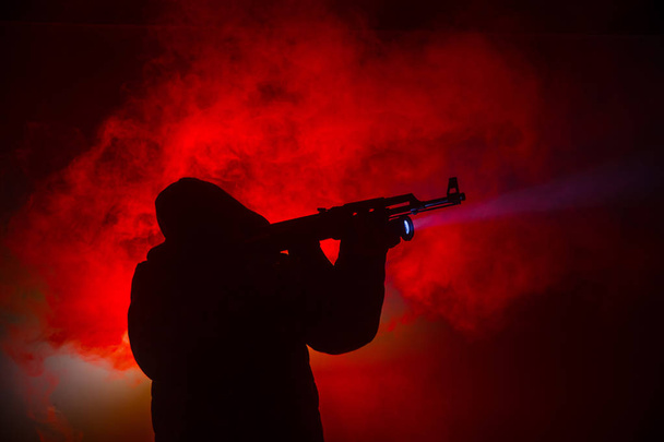 Силуэт человека с штурмовой винтовкой, готового атаковать на темном туманном фоне или опасного бандита с пистолетом в руке. Стрельба в террориста с использованием темы оружия
 - Фото, изображение