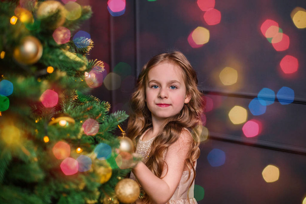Little girl under the Christmas tree. A girl with gifts under the tree in anticipation of magic, a gift from Santa Claus - Foto, Bild