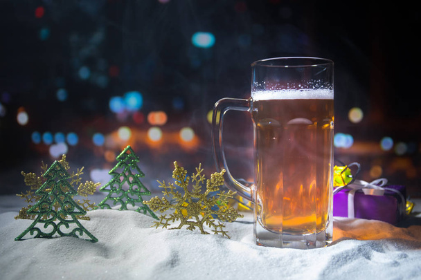 Mug of beer with Christmas decoration. Glass of light beer with foam in snow with creative New Year holiday artwork. Copy space - Foto, Imagem