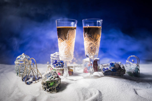 Two glasses of champagne with Christmas decoration. Traditional winter holiday alcohol drink in snow with creative New Year artwork. Copy space. Selective focus - Photo, Image