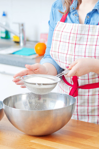 women are mixing the ingredients of a cake in a stainless bowl in her kitchen for weekend party - Foto, Imagem