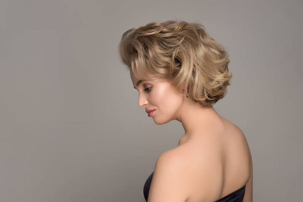 Blonde Girl with Elegant and shiny Hairstyle. Beautiful Model Woman with Curly Hairstyle. Care and Beauty Hair products. Perfect Make-Up - 写真・画像