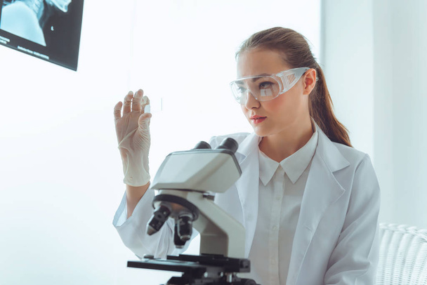 Portret młodego naukowca badania przy pomocy mikroskopu w laboratorium, biotechnologii, chemii, naukowych. - Zdjęcie, obraz