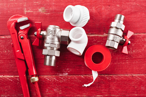 plumbing tools and equipment on a red wooden background close up - Фото, зображення