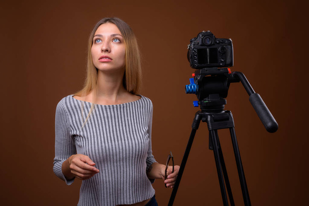 Jovem mulher bonita vlogging com câmera DSLR em estúdio
 - Foto, Imagem