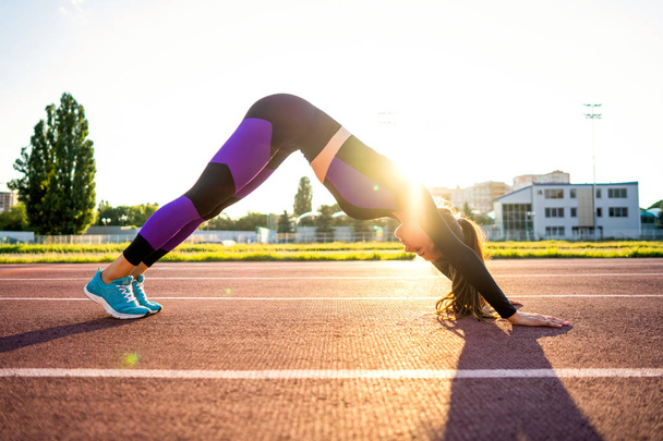 fille de sport engagé yoga dans un échauffement au stade au coucher du soleil
 - Photo, image
