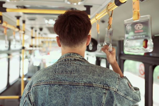 Asian man standing inside city bus. - Zdjęcie, obraz