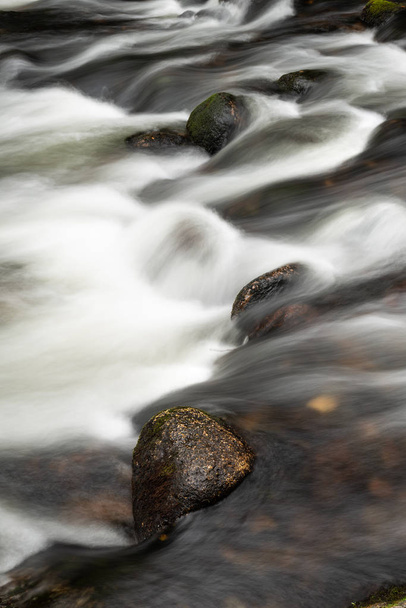 Λεπτομέρεια εικόνας τοπίο του ποταμού, που ρέει πέρα από τους βράχους με μακρά έκθεση κίνηση θάμπωμα - Φωτογραφία, εικόνα