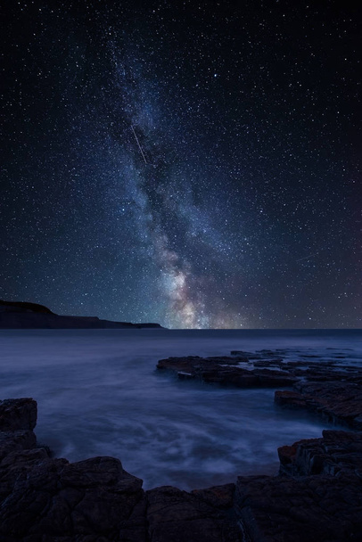 Потрясающее яркое композитное изображение Млечного пути над ландшафтом береговой линии и скалистого берега
 - Фото, изображение