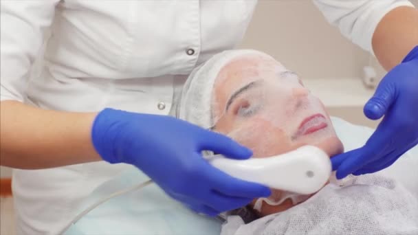 Retrato de mujer con máscara membranosa con un refinador de belleza en la cara. Proceso de ionoforesis en clínica de belleza
 - Metraje, vídeo