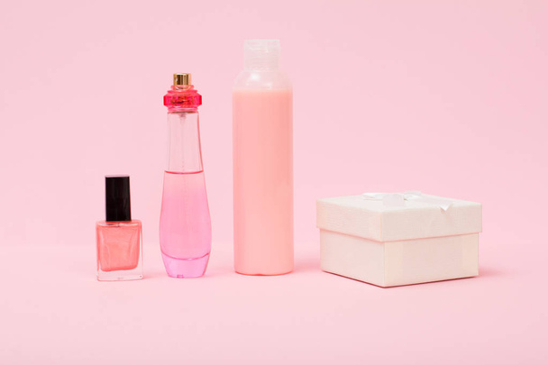 Bottles with nail polish, perfume, shampoo and gigt box on a pink background. Women cosmetics and accessories. - Foto, imagen