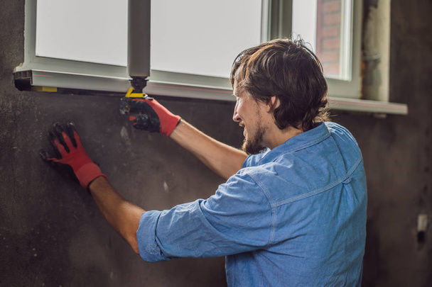Ev yenileme sırasında pencere montaj yaparken mavi gömlekli erkek işçi. - Fotoğraf, Görsel