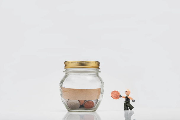 Uma figura em miniatura de um homem de Lego carrega dinheiro em um frasco de vidro por dinheiro. O conceito de investimento financeiro. Estúdio
. - Foto, Imagem