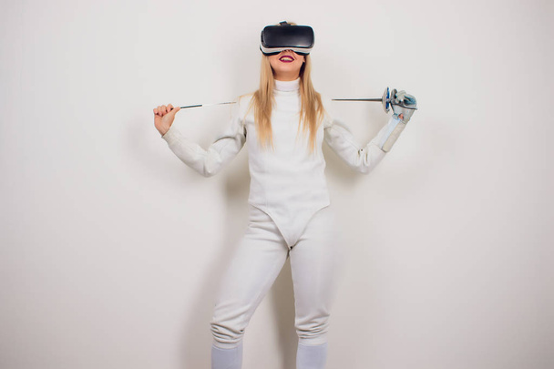 woman wearing fencing suit practicing with sword against grey vignette vr - Photo, Image