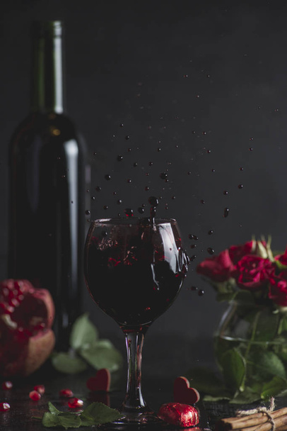 Czerwone wino w szklance. Romantyczny wieczór z lampką wina na Walentynki. Holiday składu na czarny stół i tło. Powitalny drink - Zdjęcie, obraz