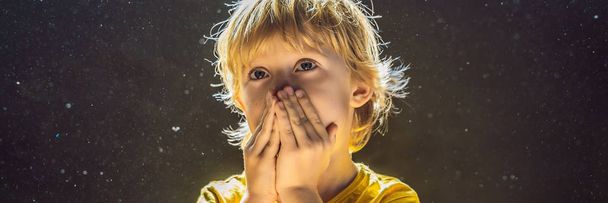 Allergie voor stof. Jongen niest omdat hij allergisch is voor stof. Stof vliegt in de lucht verlicht door licht Banner, lange notatie - Foto, afbeelding