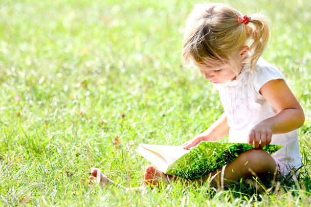 beautiful little girl in nature with book - Zdjęcie, obraz
