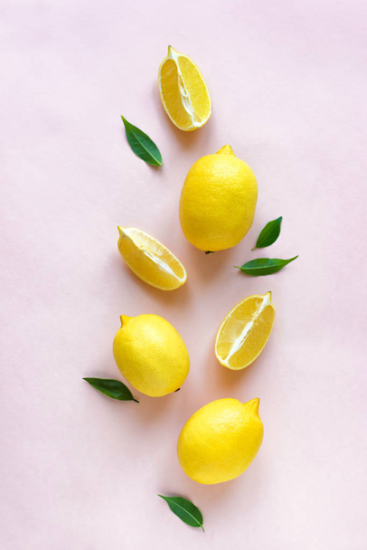Lemons with green leaves on pink pastel background, top view, flat lay. Organic fresh citrus fruits lemons, minimal conceptual flat lay. - Foto, afbeelding