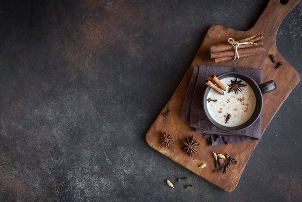 Traditional indian masala chai tea in ceramic cup with ingredients. Spicy black tea with milk (Masala) on rustic dark background, copy space. - Fotoğraf, Görsel