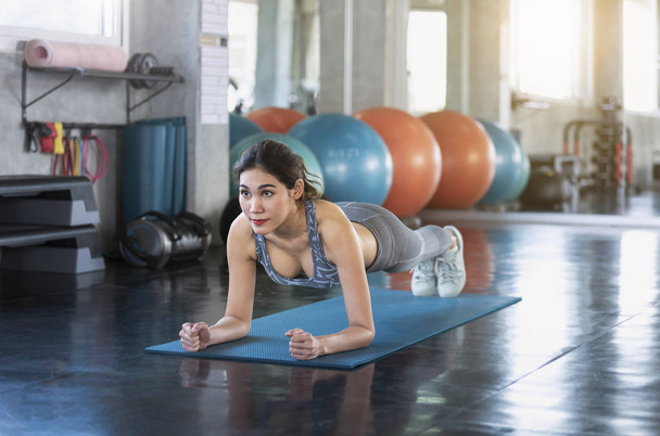 Sport. Young asian athletic woman doing push-up muscular exercising in fitness gym. - 写真・画像