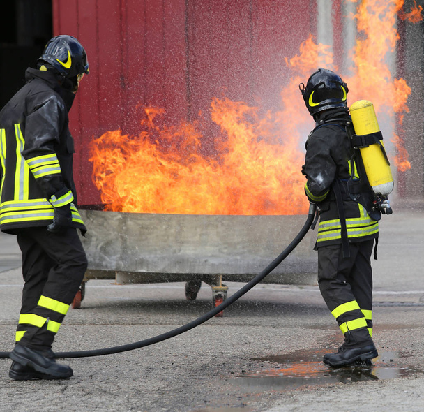два пожарных с бутылками кислорода от огня во время учений
 - Фото, изображение