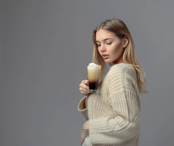 Ír kávé vonzó fiatal nő. Gyönyörű szőke egy pulóvert, gazdaság, egy bögre kávét tejszínnel. Másolja a hely. - Fotó, kép