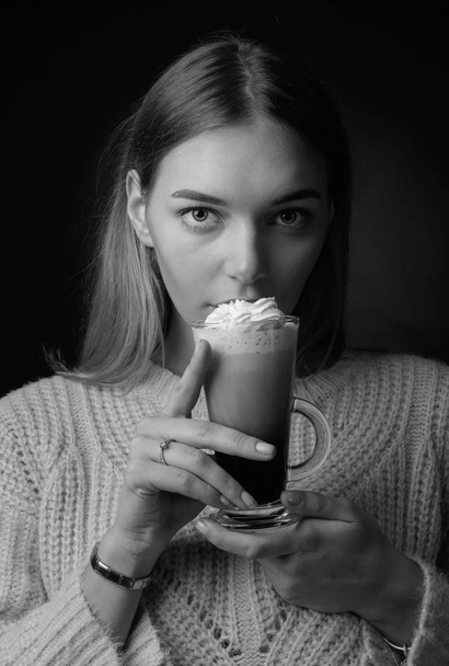 Attractive young woman with Irish coffee. Beautiful blonde in a sweater holding a mug of coffee with cream. - Photo, Image