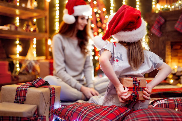 Cheerful mom and her cute daughter girl exchanging gifts. Loving family with presents in christmas room. - Fotoğraf, Görsel