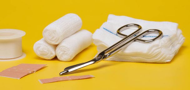 Plasters and bandages with Scissors and syringe on a yellow background - Photo, Image